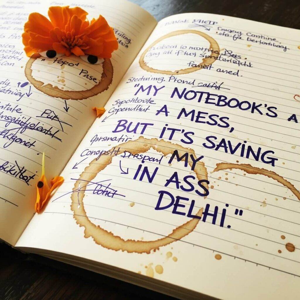 Notebook with quote, chai stains, and marigold petal.
